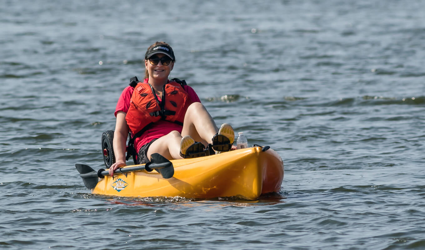 Woman wearing a red shirt and a cap on a yellow kayak