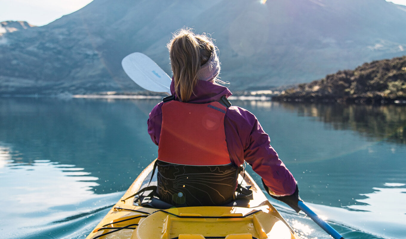 A woman wearing a red wetsuit on a yellow kayak