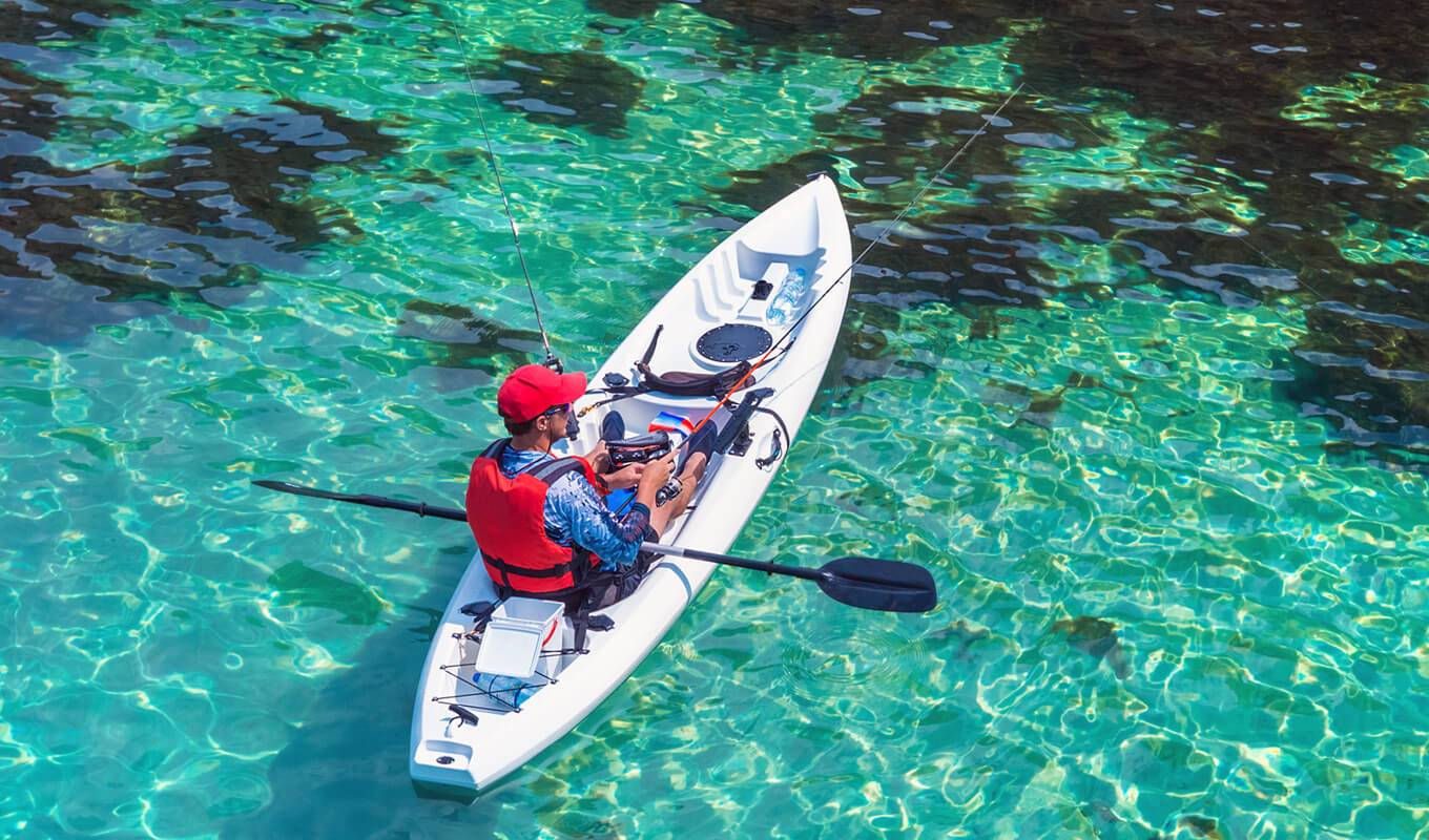 Man wearing a red life jacket fishing on a kayak