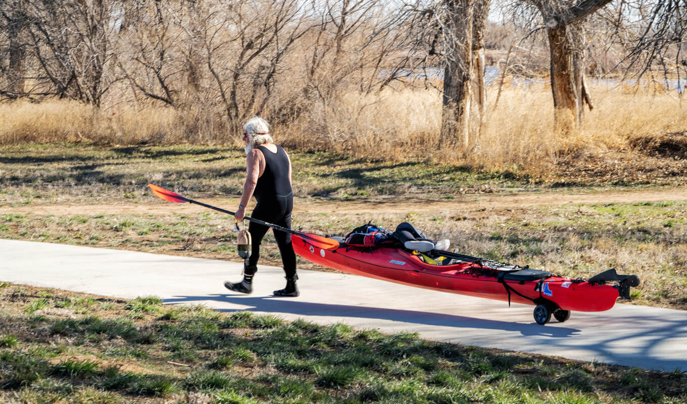 Old man moving his kayak with a kayak cart