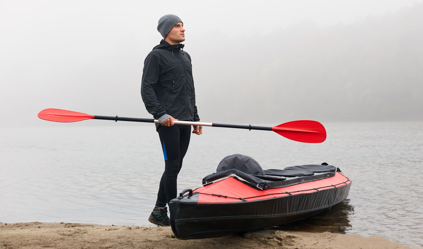 Man holding an aluminum kayak paddle with a red blade