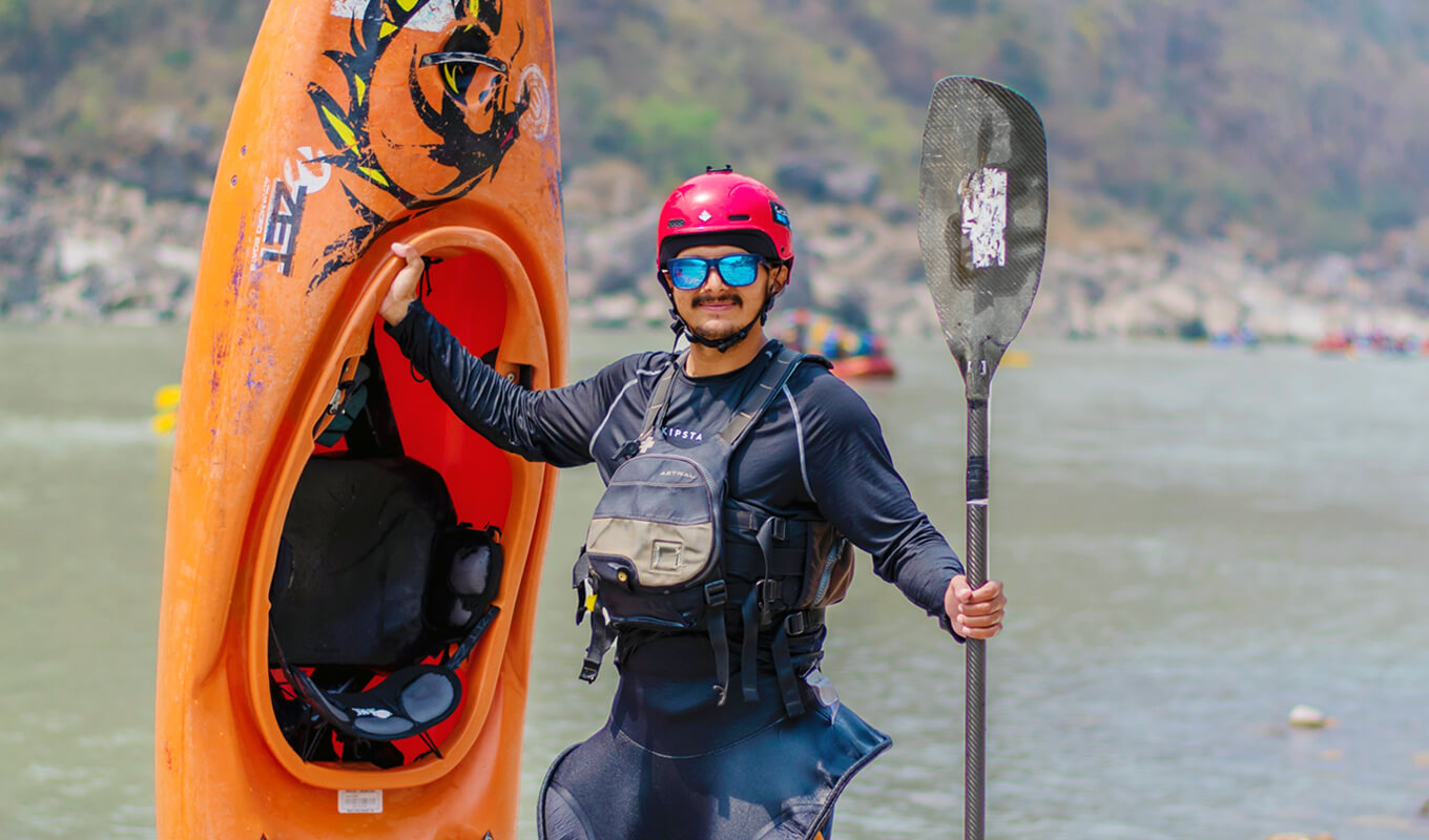 Man holding a orange kayak and a black kayak paddle