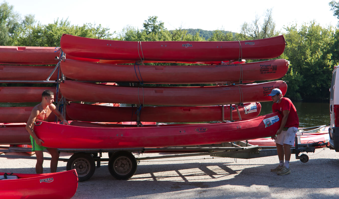 Man transporting a red kayak on a kayak trailer