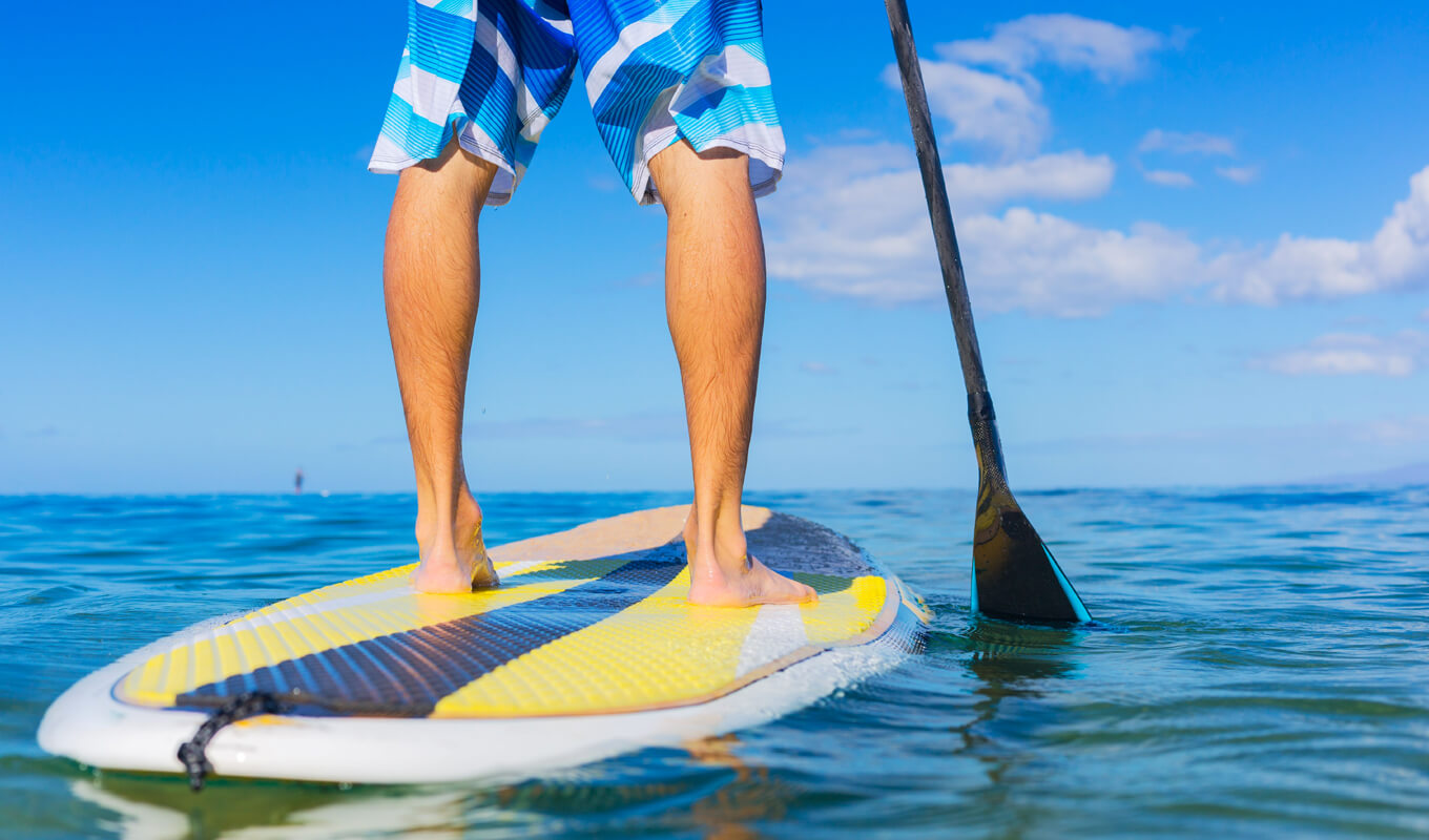 Mann-Paddle-Boarding mit einem gelben Softtop-Paddle-Board