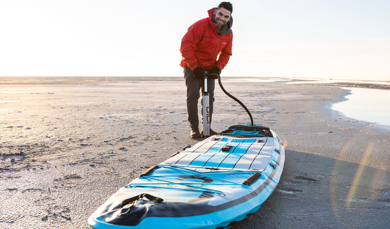 Man wearing a winter clothes while inflating GILI adventure inflatable board