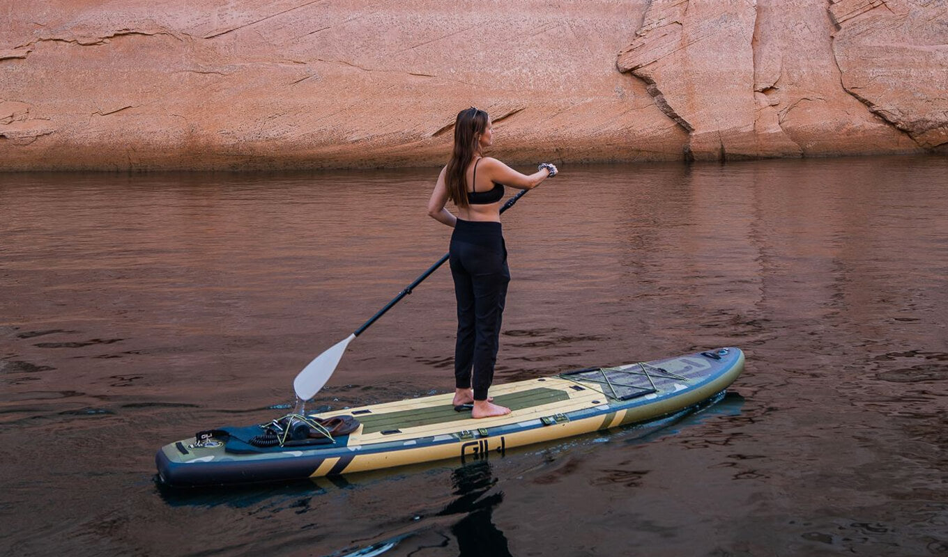 Woman paddle boarding on a lake near a rocky mountain