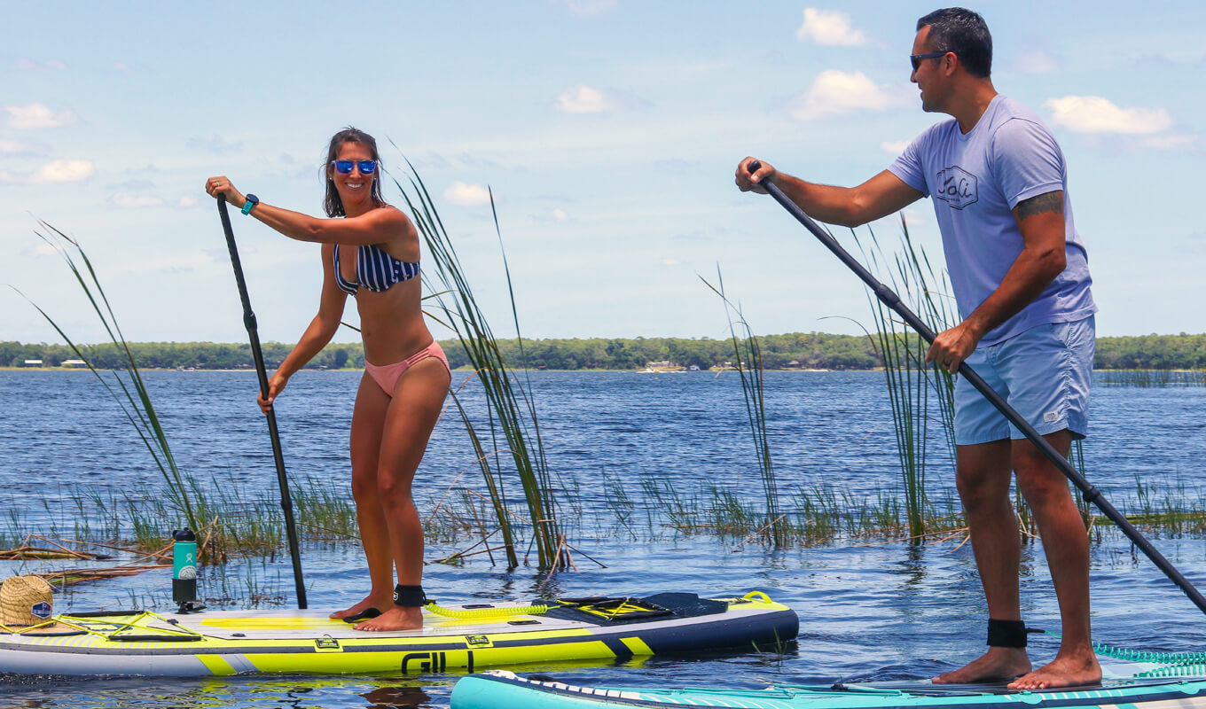 Man and a woman paddle boarding on a lake