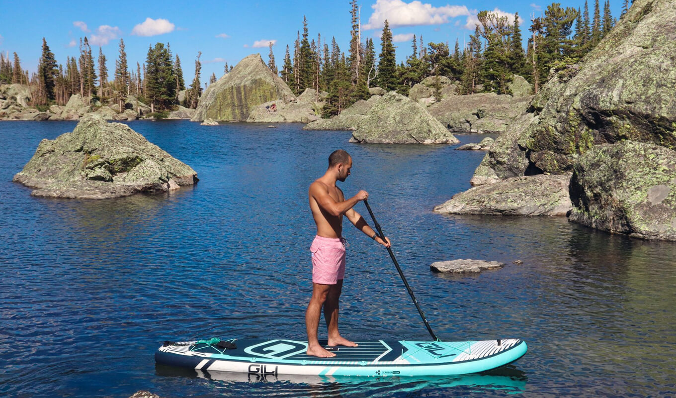 Man on a pink short paddle boarding on a lake