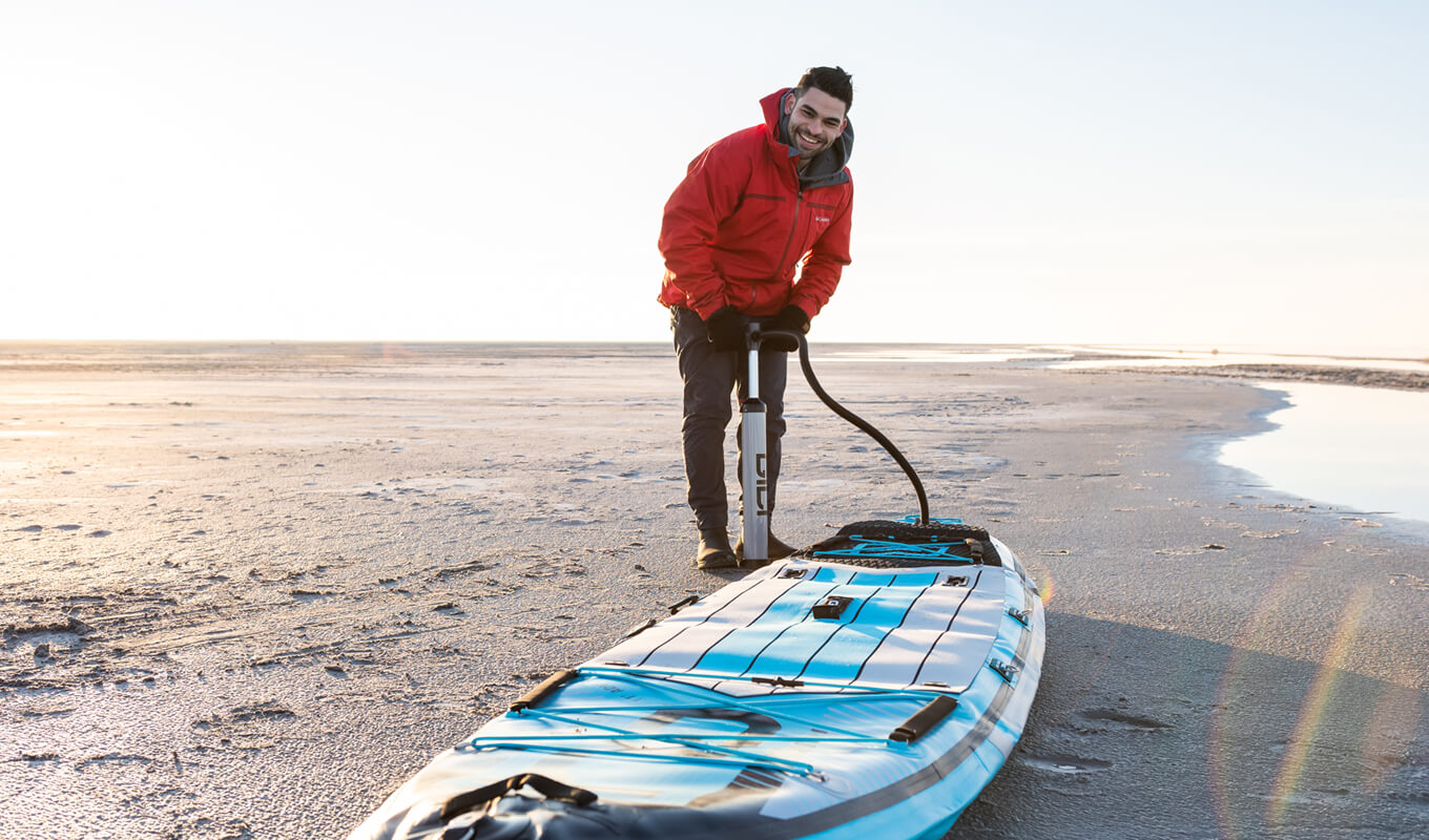 Man inflating his GILI inflatable paddle board with a manual pump