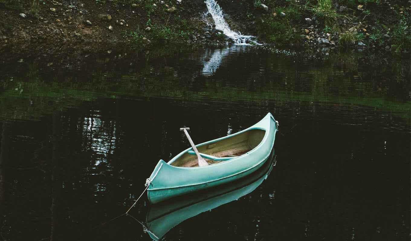 Green solo canoe on a lake
