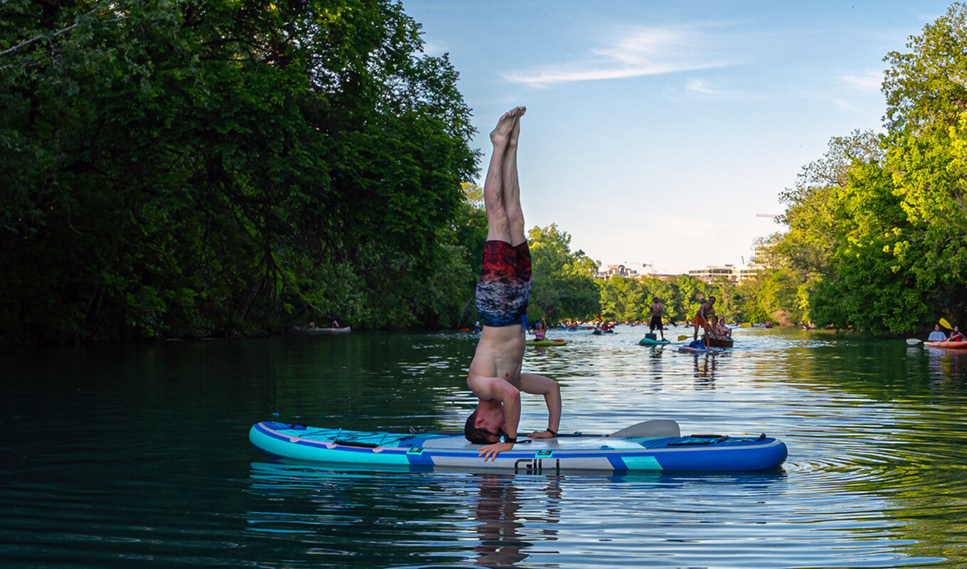 Man performing a headstand pose on his yoga inflatable paddle board