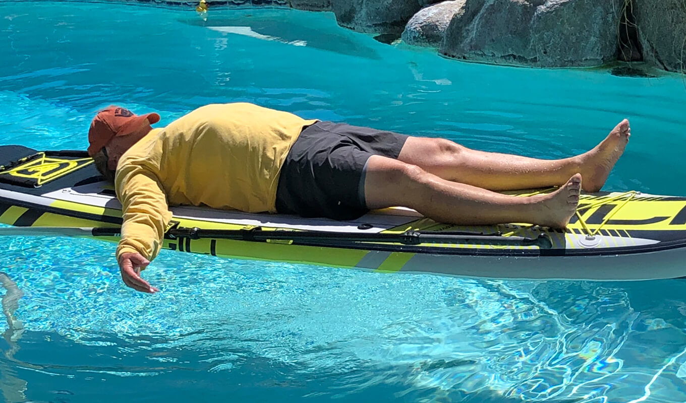 Man performing Savasana pose on his inflatable SUP