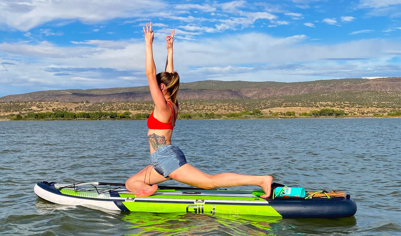 Woman on a red top performing a crescent lunge on a gili inflatable SUP
