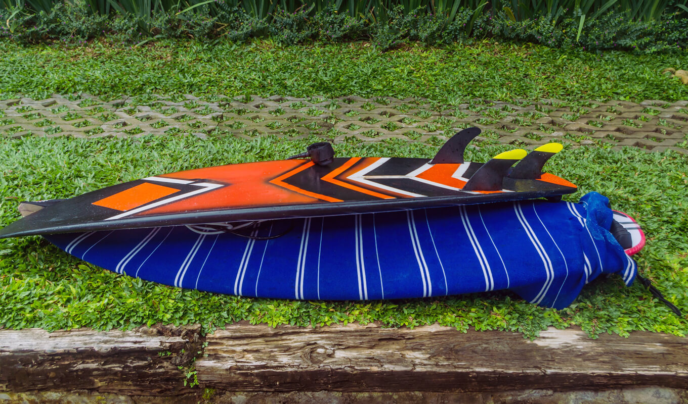 Orange surfboard on top of the blue surfboard bag