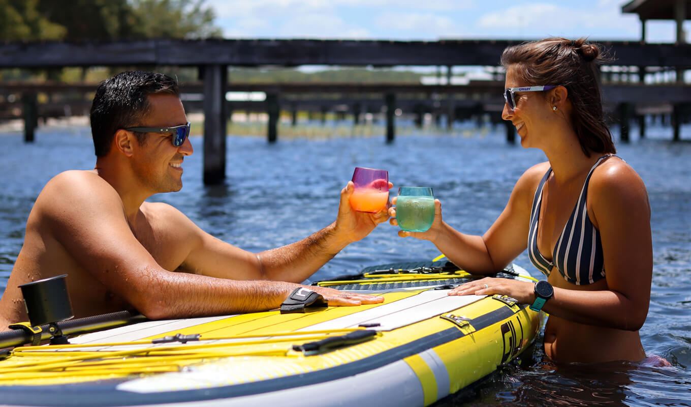 Man and a woman drinking while paddle boarding in summer