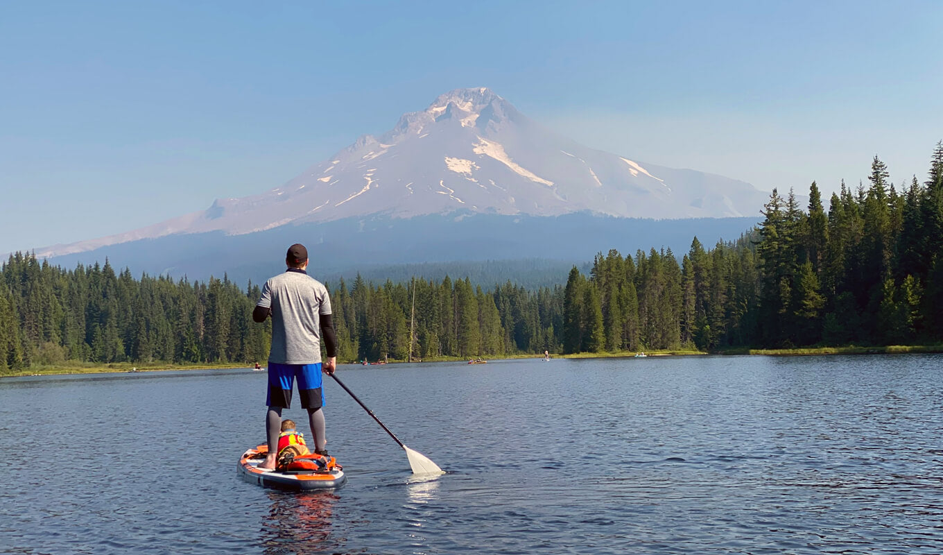 Man paddle boarding with his child on a lake 