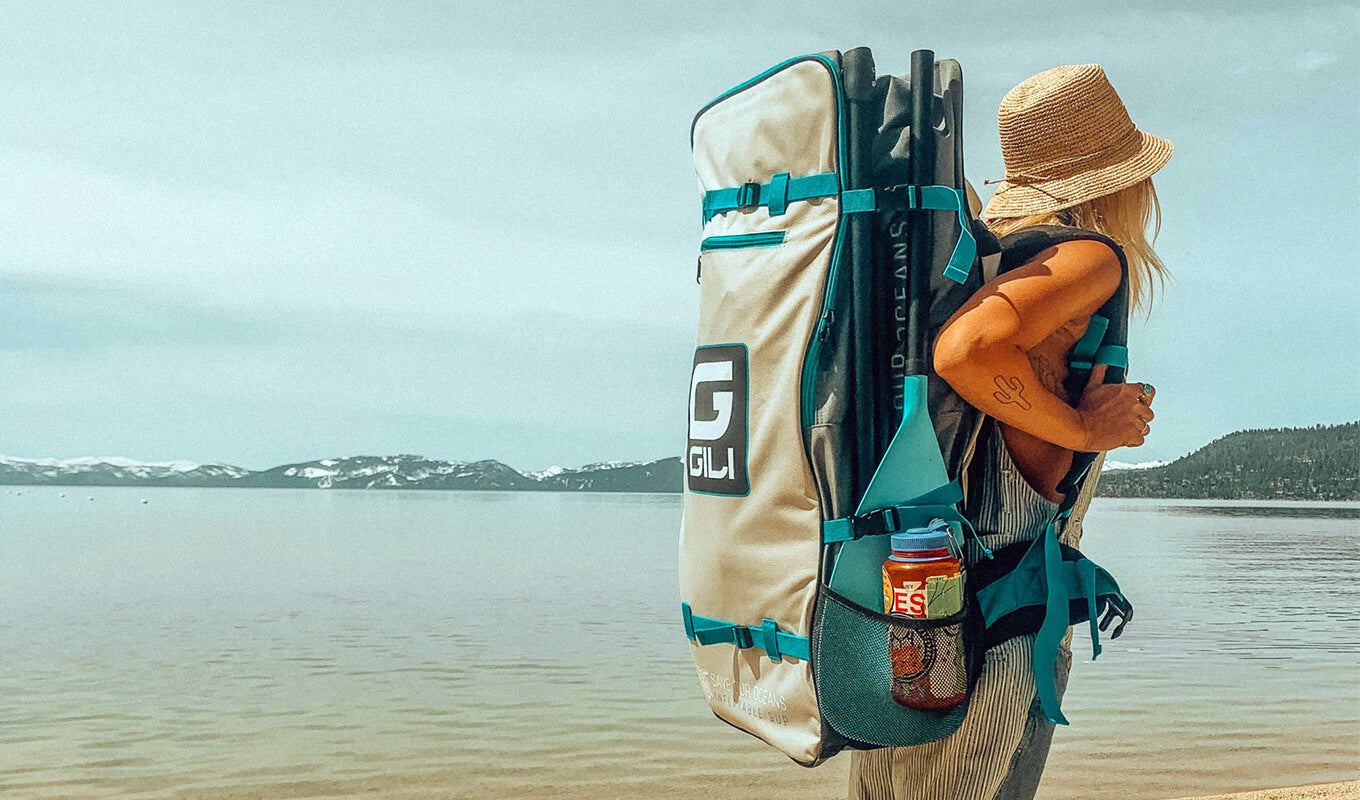 Frau, die einen SUP-Rucksack mit Paddel auf der Tasche trägt