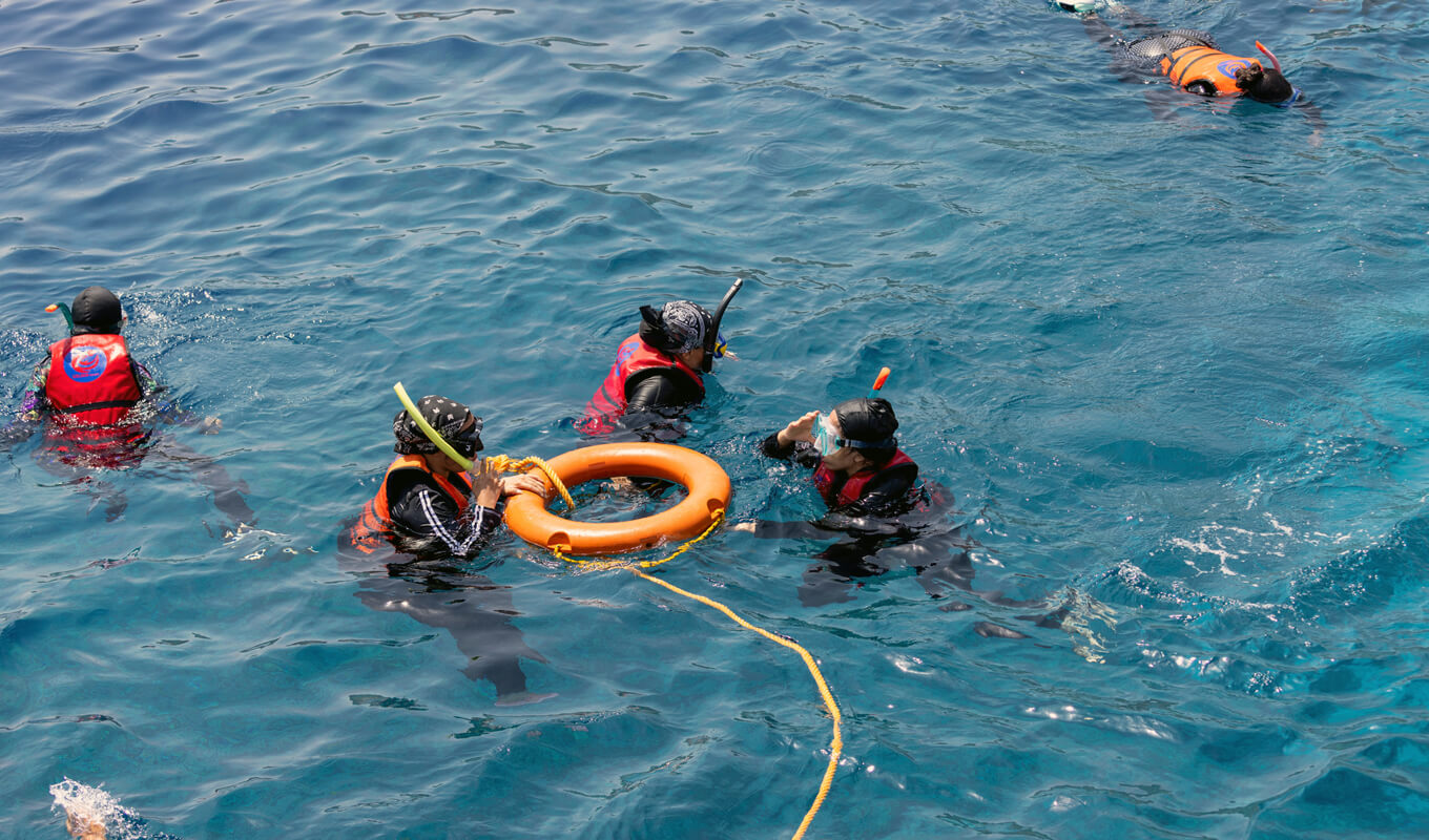 Menschen, die mit einer Rettungsboje schnorcheln, die auf dem Wasser schwimmt