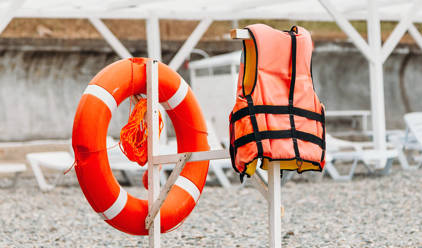 Rettungsboje und eine Schwimmweste hängen nach dem Spülen an einem Holz