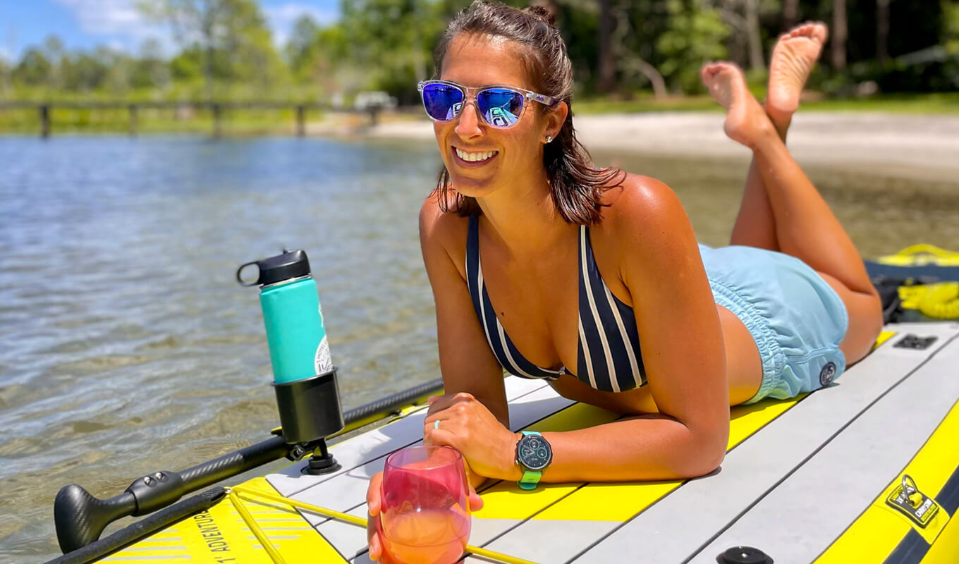 Woman paddle boarding with a water bottle 