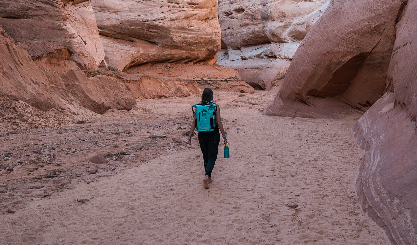 Frau, die mit einem blaugrünen Rolltop-Rucksack von GILI geht