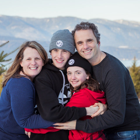 Family of four huddled together in Shuswap Soul sweaters and hats posing for a holiday card