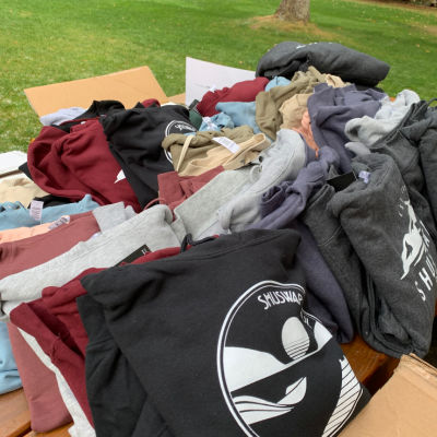 Shuswap Soul Hoodies folded up in size piles on a picnic table in Herald Park before a photoshoot