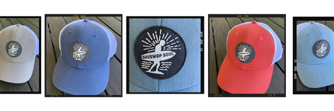 Shuswap Soul hats with a surfer design patch on the front. There are 4 hats in the photo - one in blue, grey, denim and mango