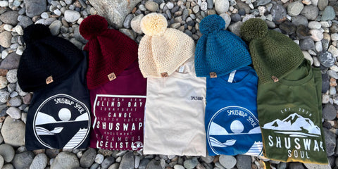 five made in canada touques are placed on rocks with matching Shuswap Soul tees - the toque and shirt colours are black, maroon, cream, teal and olive.