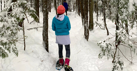 A girl in a blue jacket snowshoes on a forest trail at the Larch Hills Cross Country Ski Area near Salmon Arm British Columbia