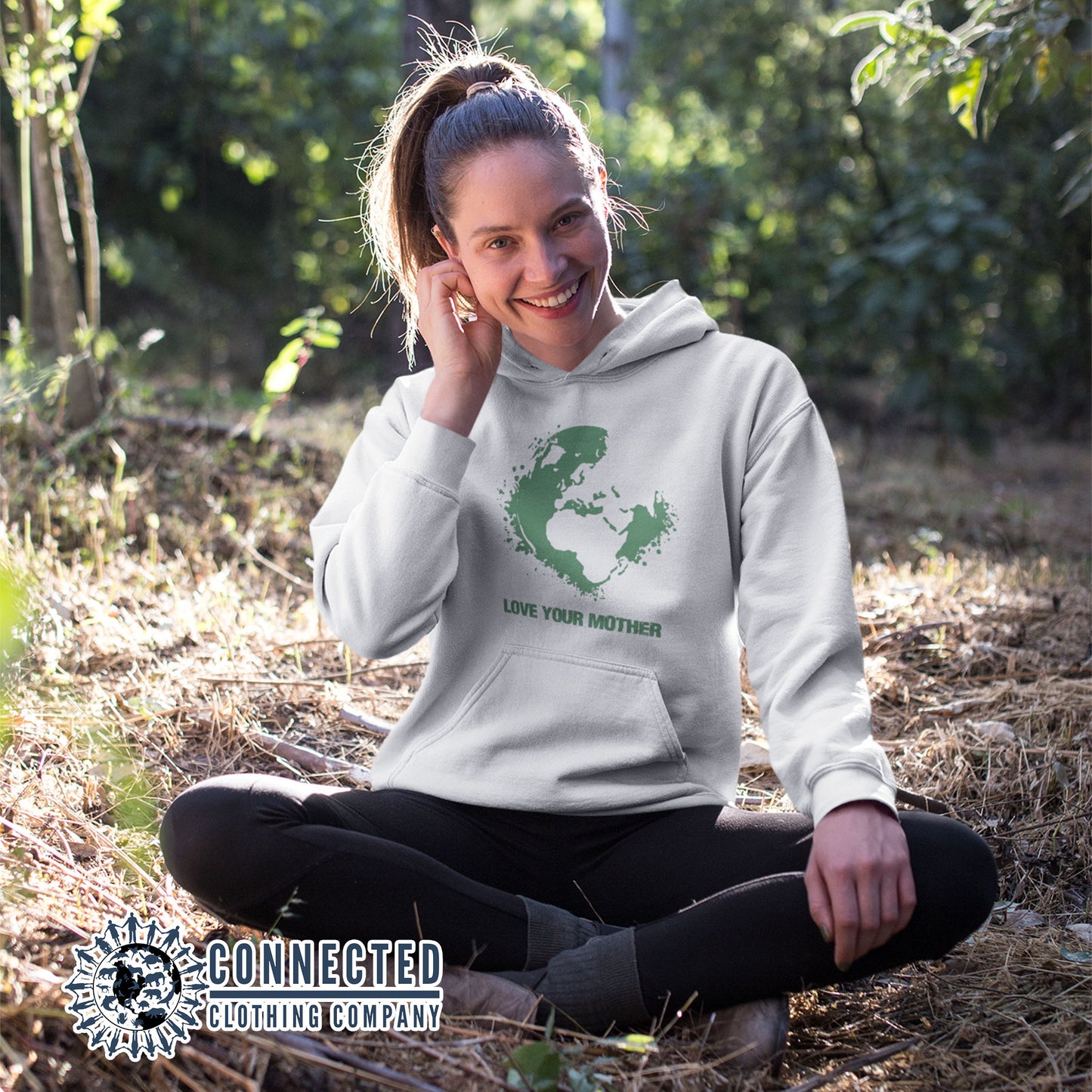 Model in the forest wearing White Love Your Mother Earth Unisex Hoodie - sweetsherriloudesigns - Ethically and Sustainably Made - 10% donated to the Environmental Defense Fund