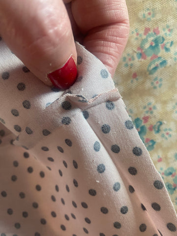 A close up image of a seam inside a pale pink garment