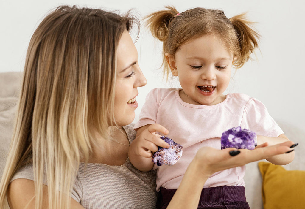 woman carrying a kid while holding a amethyst crystal in the right hand