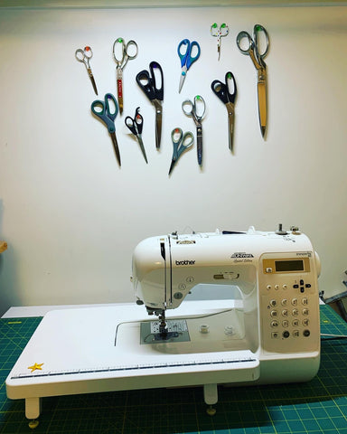 Scissors hung on the wall behind the sewing machine