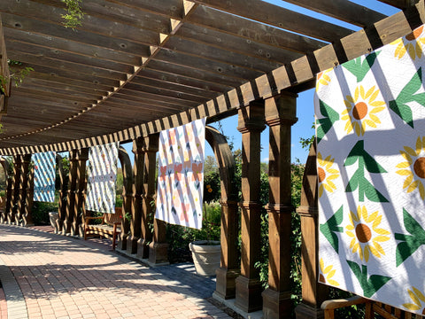 Quilts hanging in a covered walkway