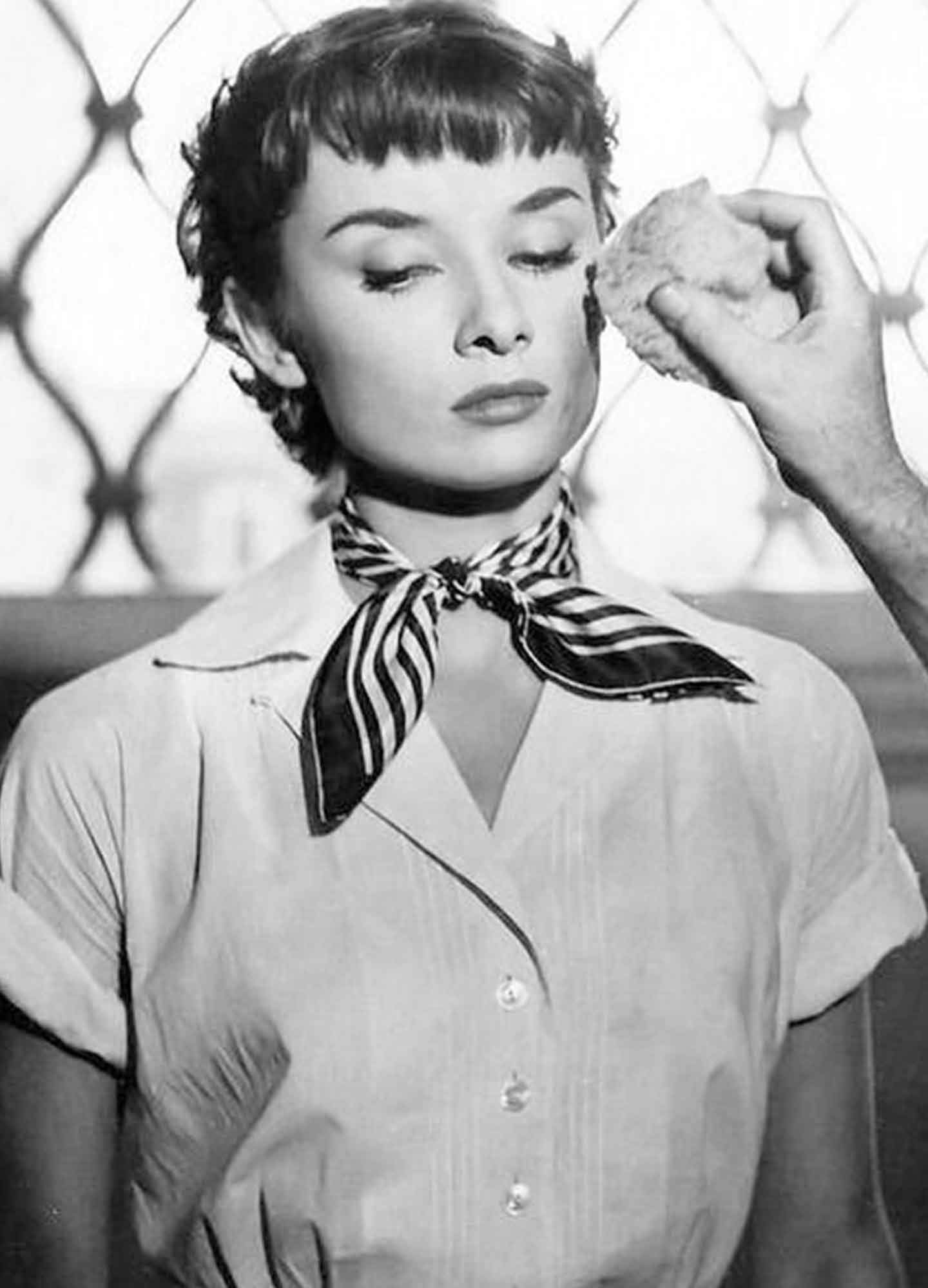 Audrey-Hepburn-wearing-a-white-shirt-and-silk-scarf-tied-around-her-neck-