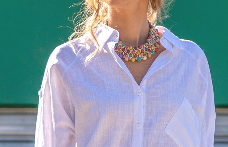 White blouse paired with a colorful statement necklace, outdoors.