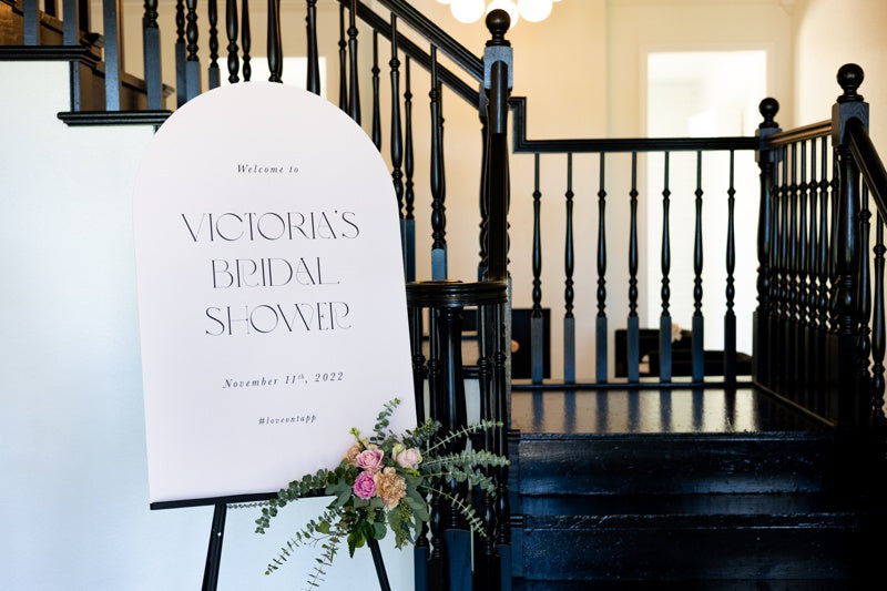 Arch shape bridal shower welcome sign with pink roses and silver dollar eucalyptus