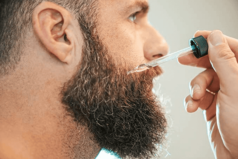 A man putting Johnny Slicks beard oil on his beard.