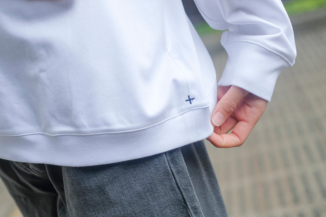 三津家貴也氏が+CLOTHETのスビンプラチナムスムース ミドルスウェットシャツのロゴマークを見ている様子