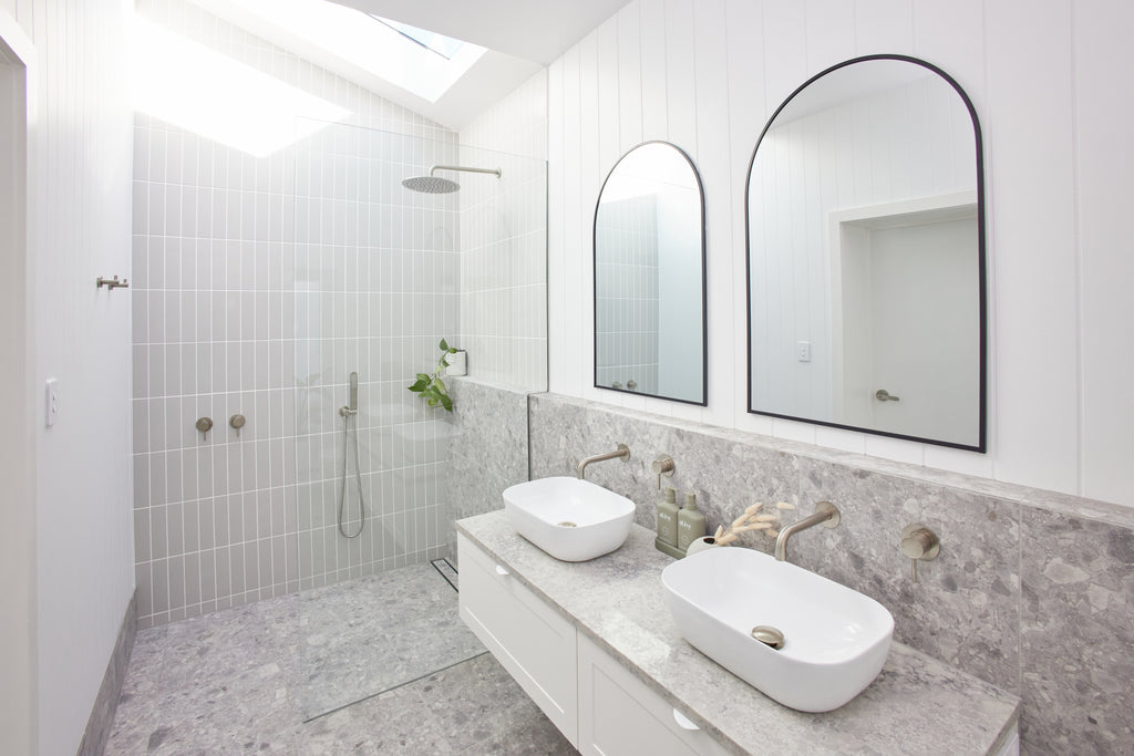 A light, bright bathroom with a double vanity and a skylight.