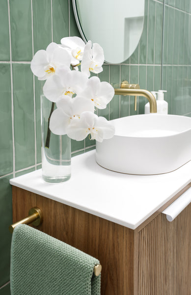 bathroom featuring green subway tiles, white basin and brushed brass tapware