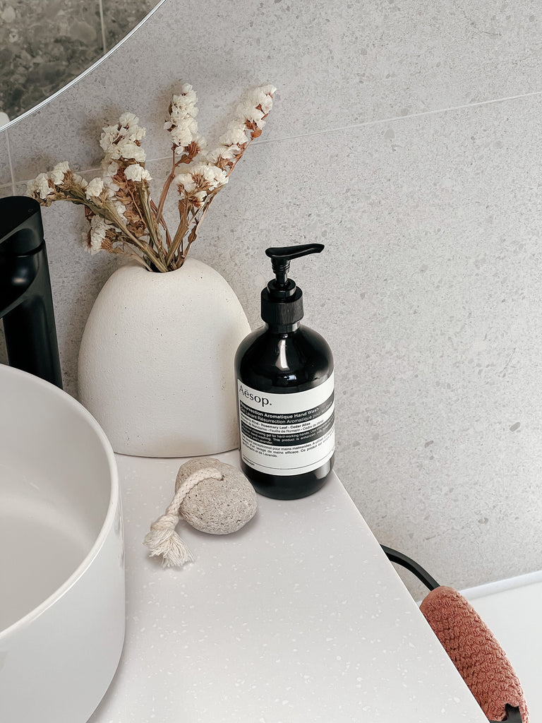 Modern bathroom with concrete-look tiles and a white stone bench.