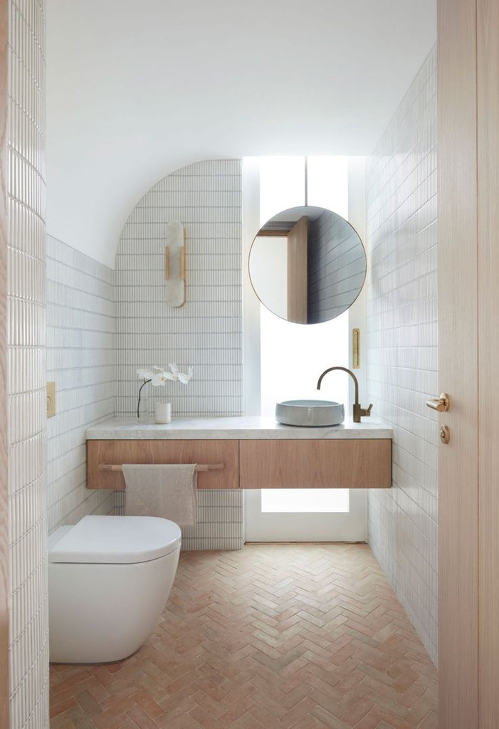 Minimalist bathroom with herringbone tile floor and white tile walls.