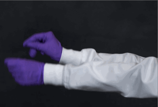 woman wearing lab coat with knit cuffs and nitrile gloves dancing