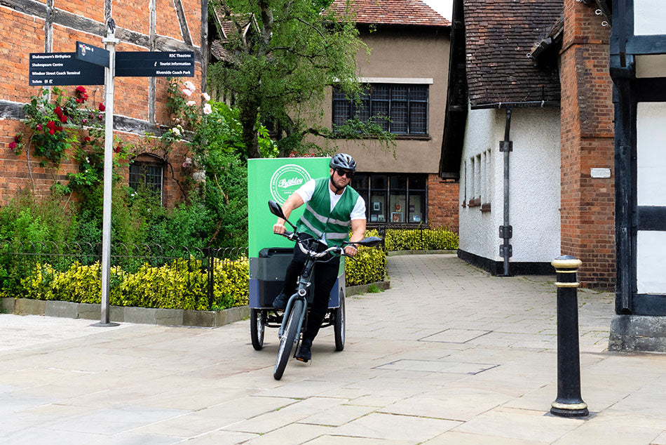 Tilting e-cargo trike and rider leaning around a corner as they cycle around Stratford-upon-Avon.