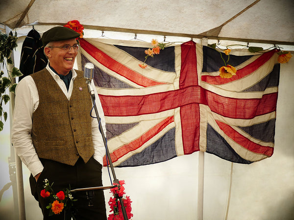 Pashley's Chairman Adrian Williams dress in tweed standing in front of a vintage union jack flag.