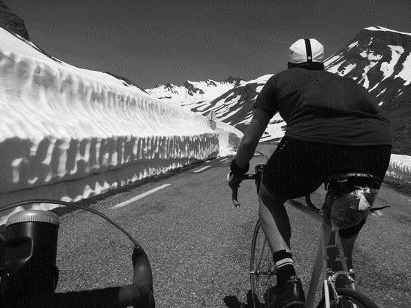 Angel Rider cycling up Galibier mountain pass on a Pashley Clubman with 5 meter snow banks either side.