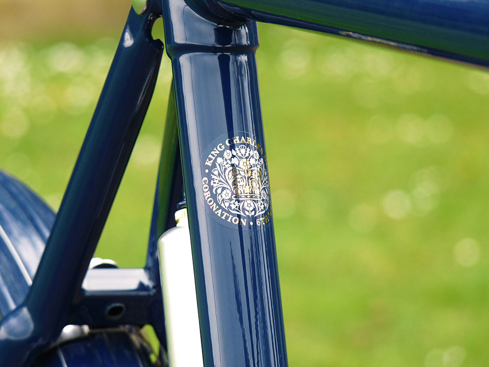 A close-up of the King's coronation logo on seat tube of the blue Kingsman bicycle.