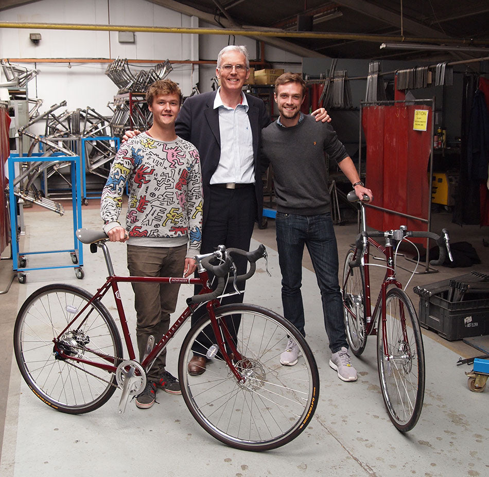 Adrian Williams standing with Paul and Tom from the Handlebards, in the Pashley bike factory with two Pashley Pathfinder bikes.
